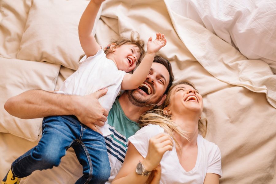 Happy family having fun in the bedroom while they lie on bed