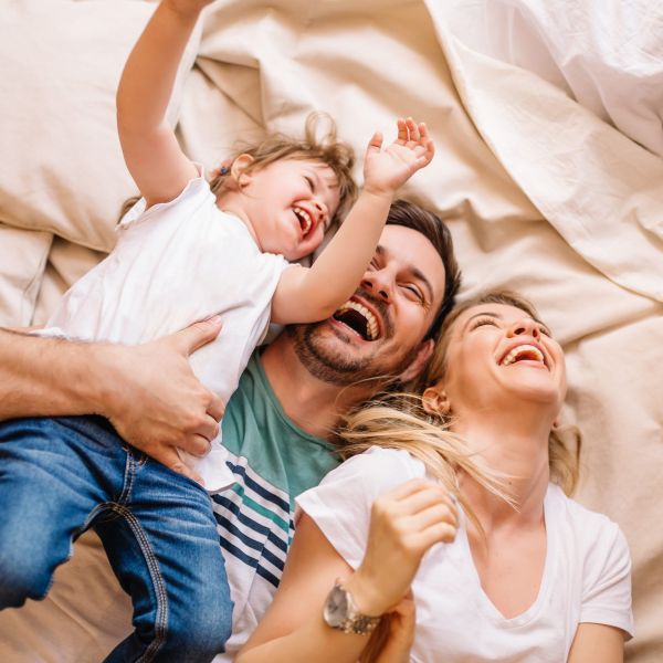 Happy family having fun in the bedroom while they lie on bed